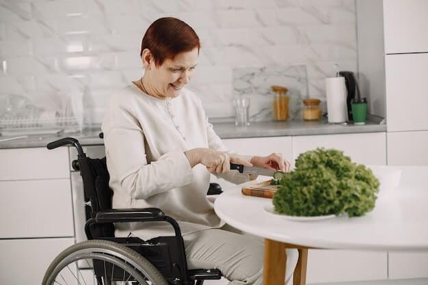 Lady cutting cucumber whilst sitting in a wheelchair